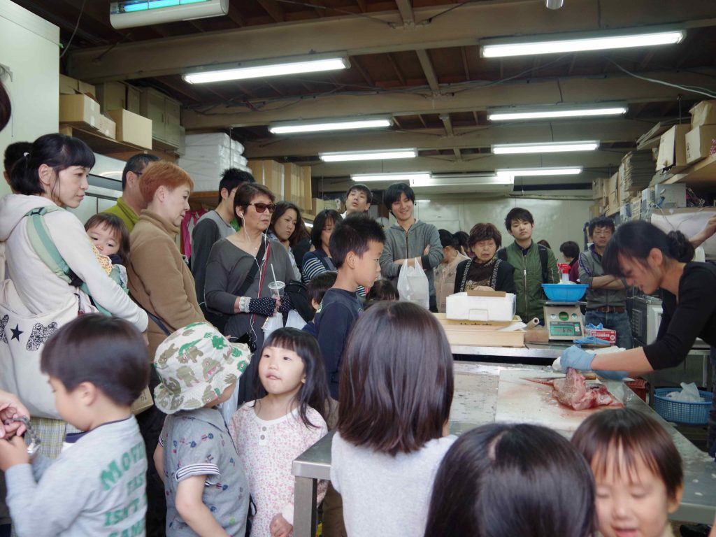 マルシェの目玉にもなっている、江美子さんの鮮魚解体ショー。大人から子どもまでたくさんの人が見守っています。